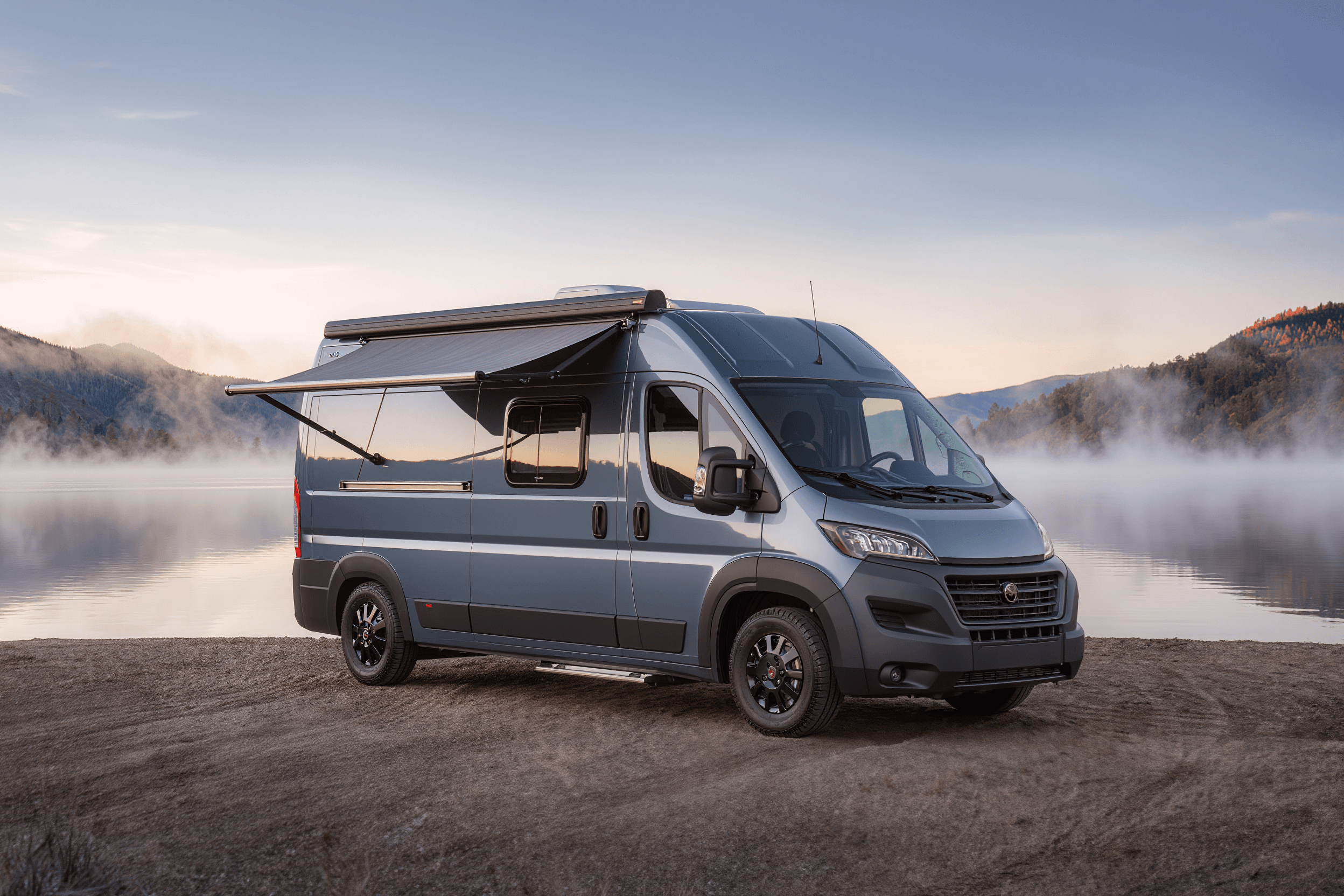 Slate blue Ram ProMaster 159 camper van beside a foggy lake