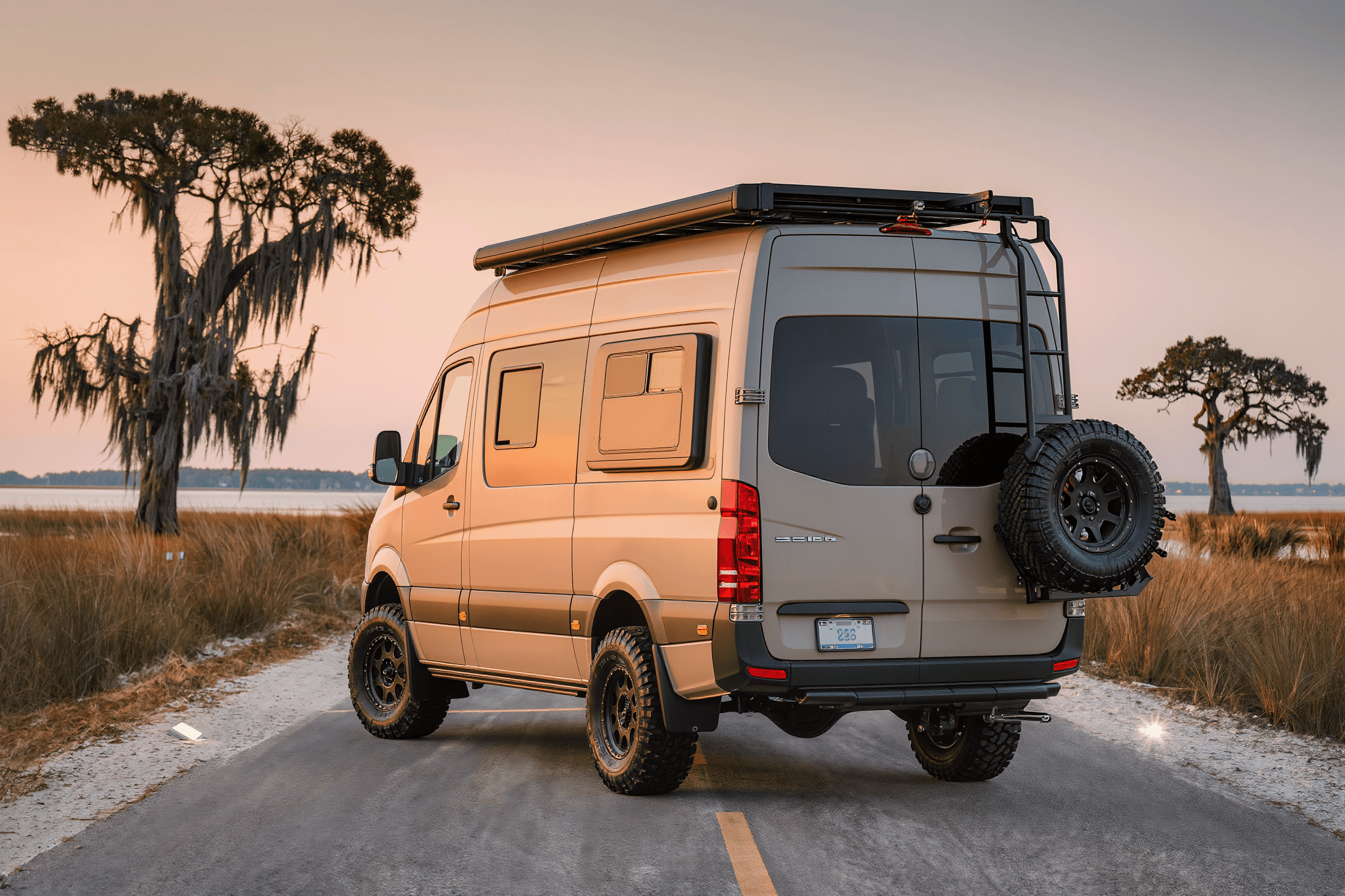 Desert tan Sprinter 144 camper van on a coastal marsh causeway